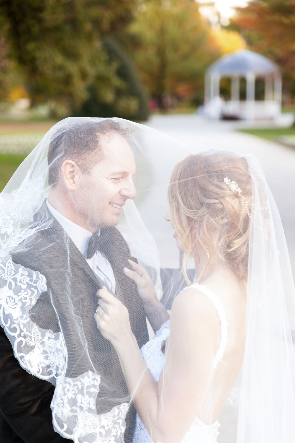 destination wedding couple embrace under a veil