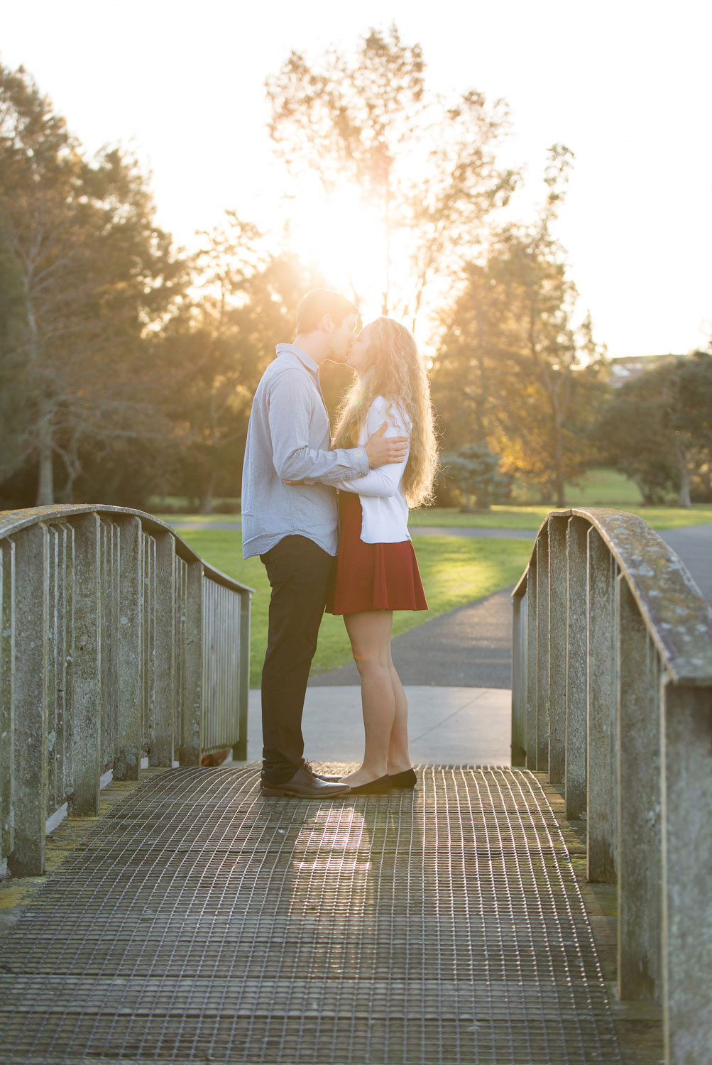auckland engagement photo couple kissing on bridge sunset