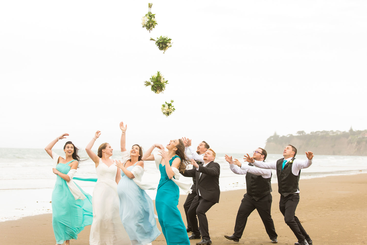 auckland wedding bridal party bouquet toss on beach
