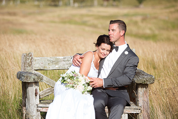 bride and groom sitting on a bench in taupo
