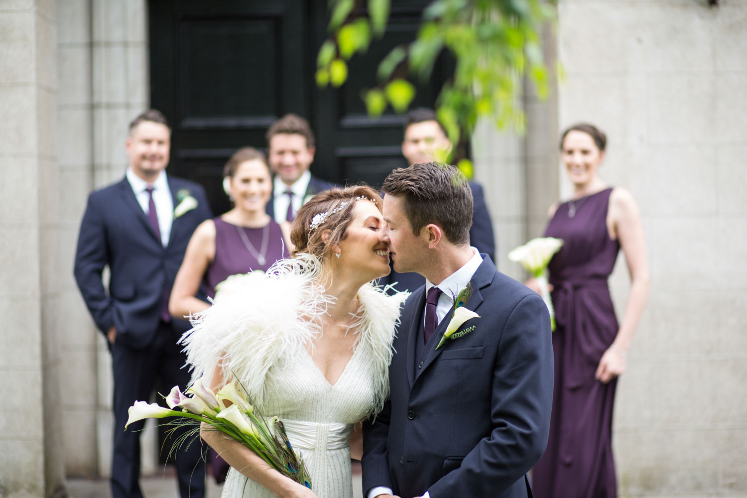 couple kissing bridal party look on