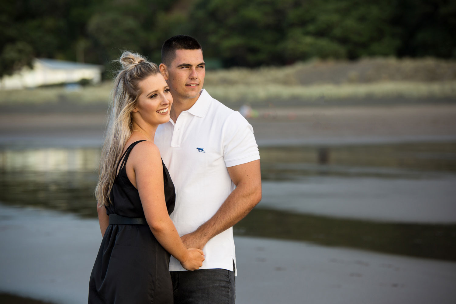 couple looking towards sunset piha