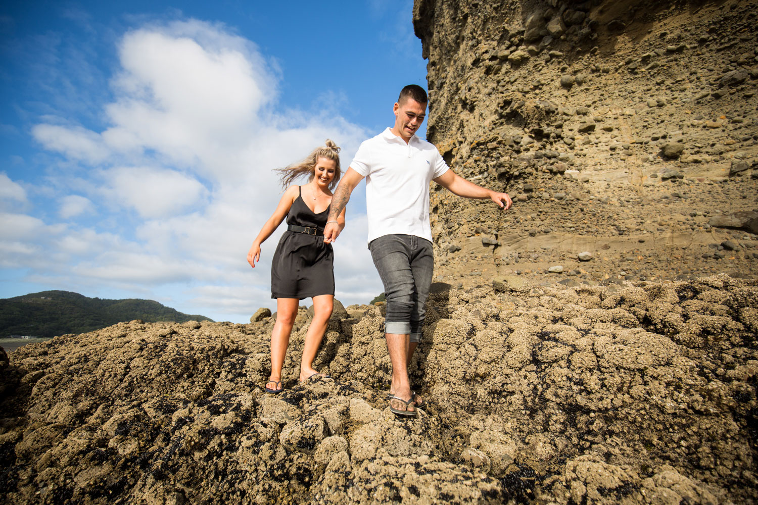 couple walking down rocks piha