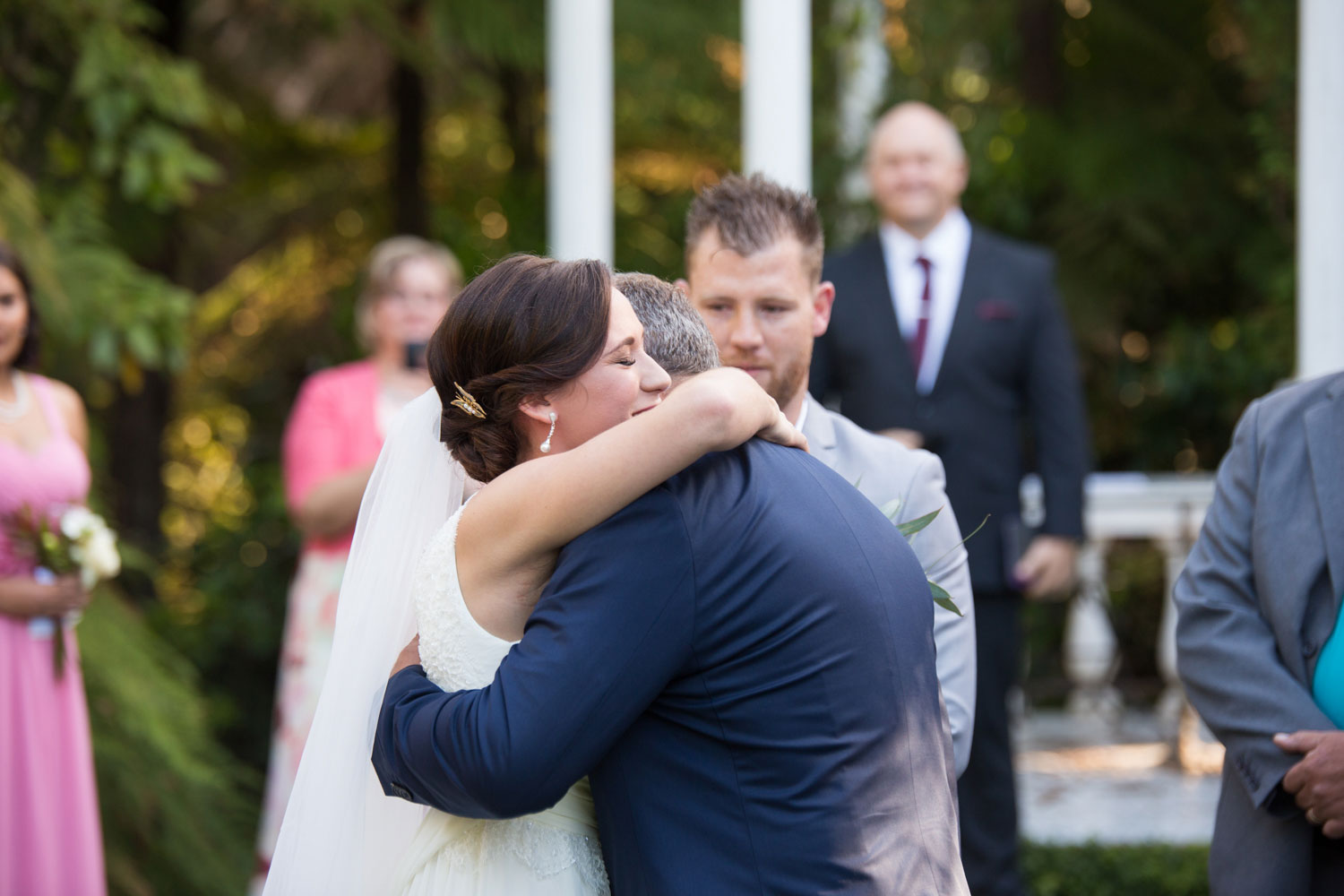groom looking at bride hugging father