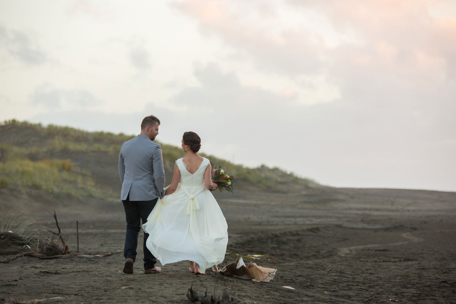 couple walking on bethells beach holding hands