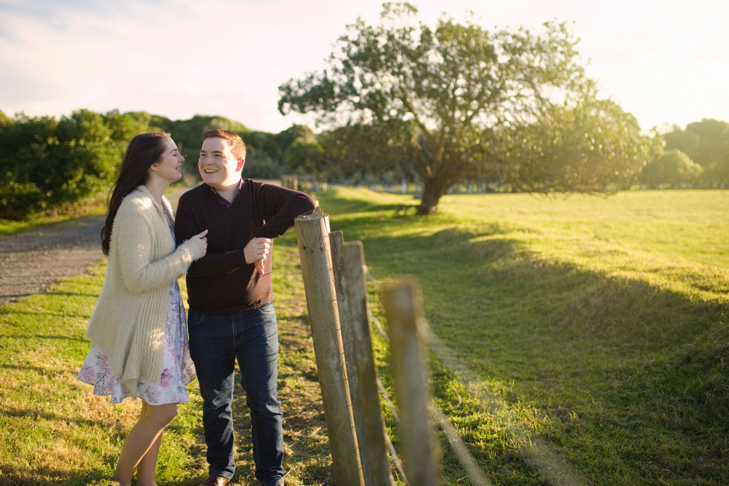 auckland engagement session couple leaning against fence