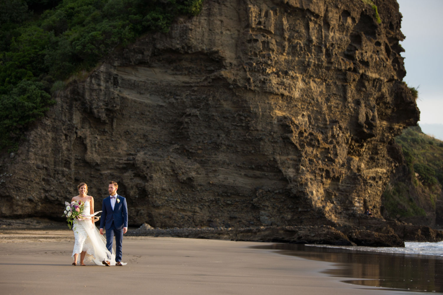auckland wedding couple walking on piha beach