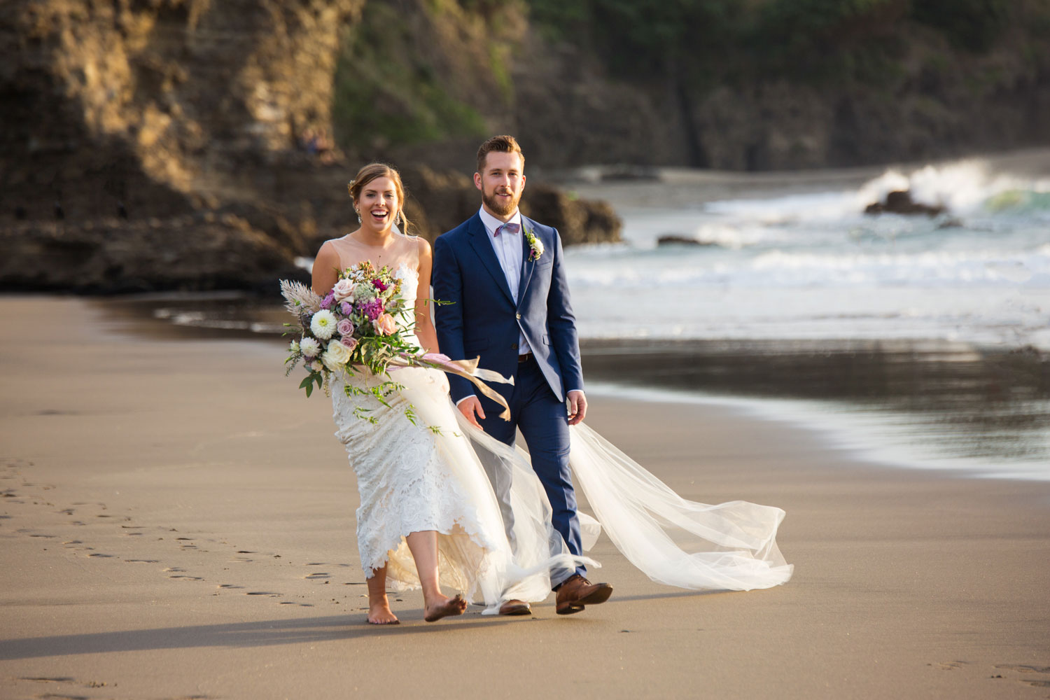 auckland wedding bride and groom walking on piha beach