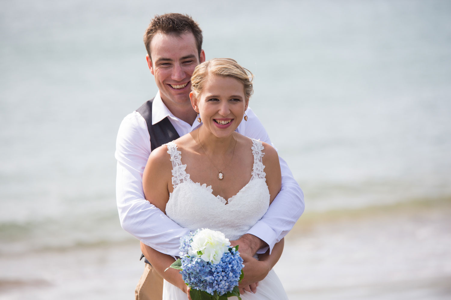 beach wedding groom and bride looking at camera