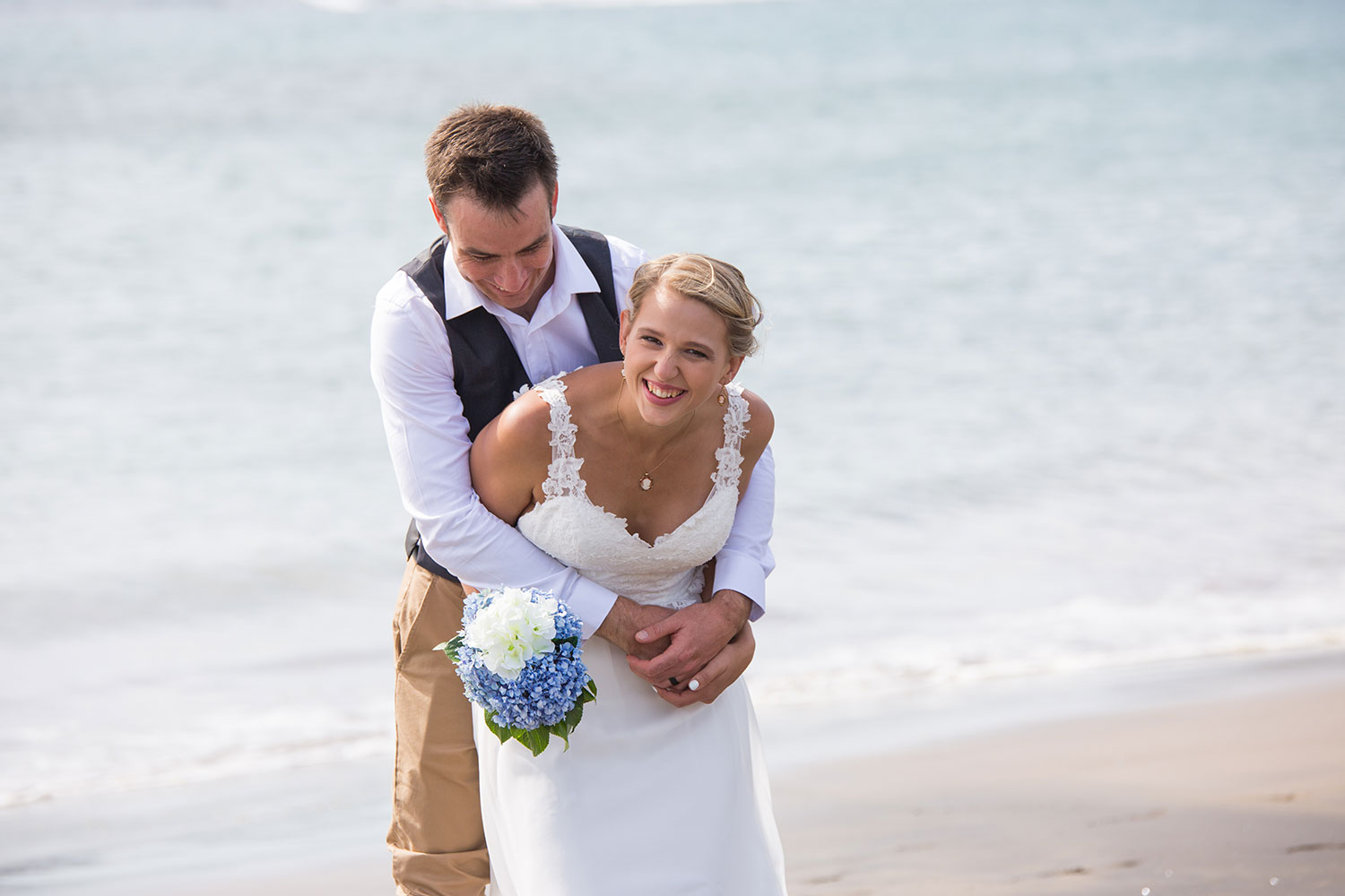 beach wedding groom hugging bride