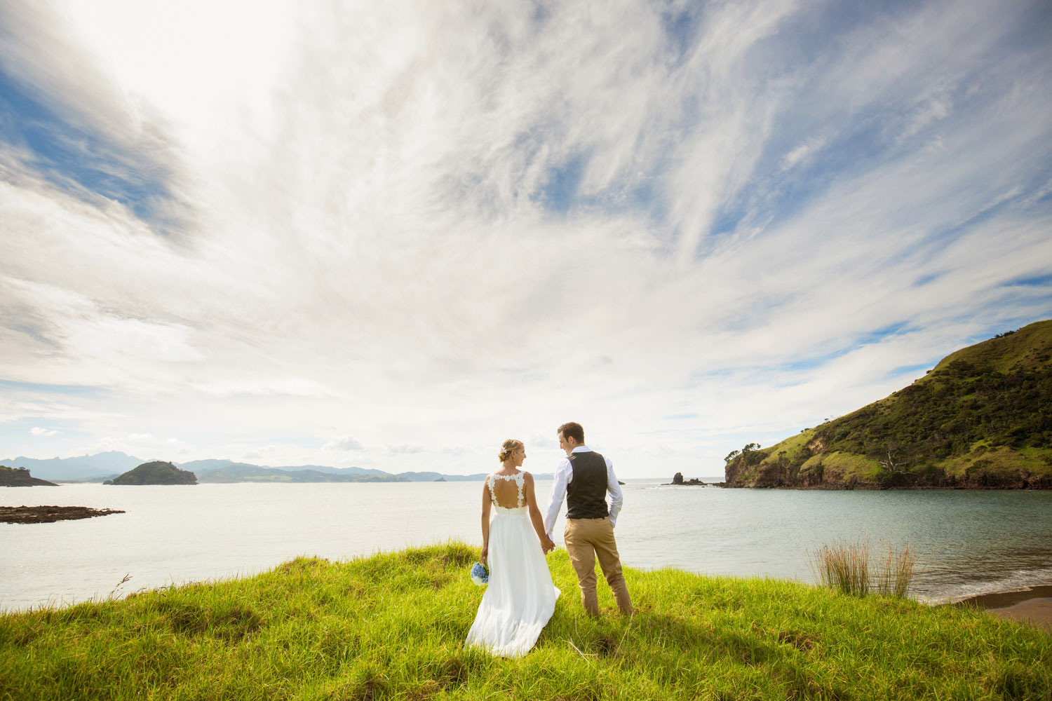 new zealand wedding couple standing on edge of coast