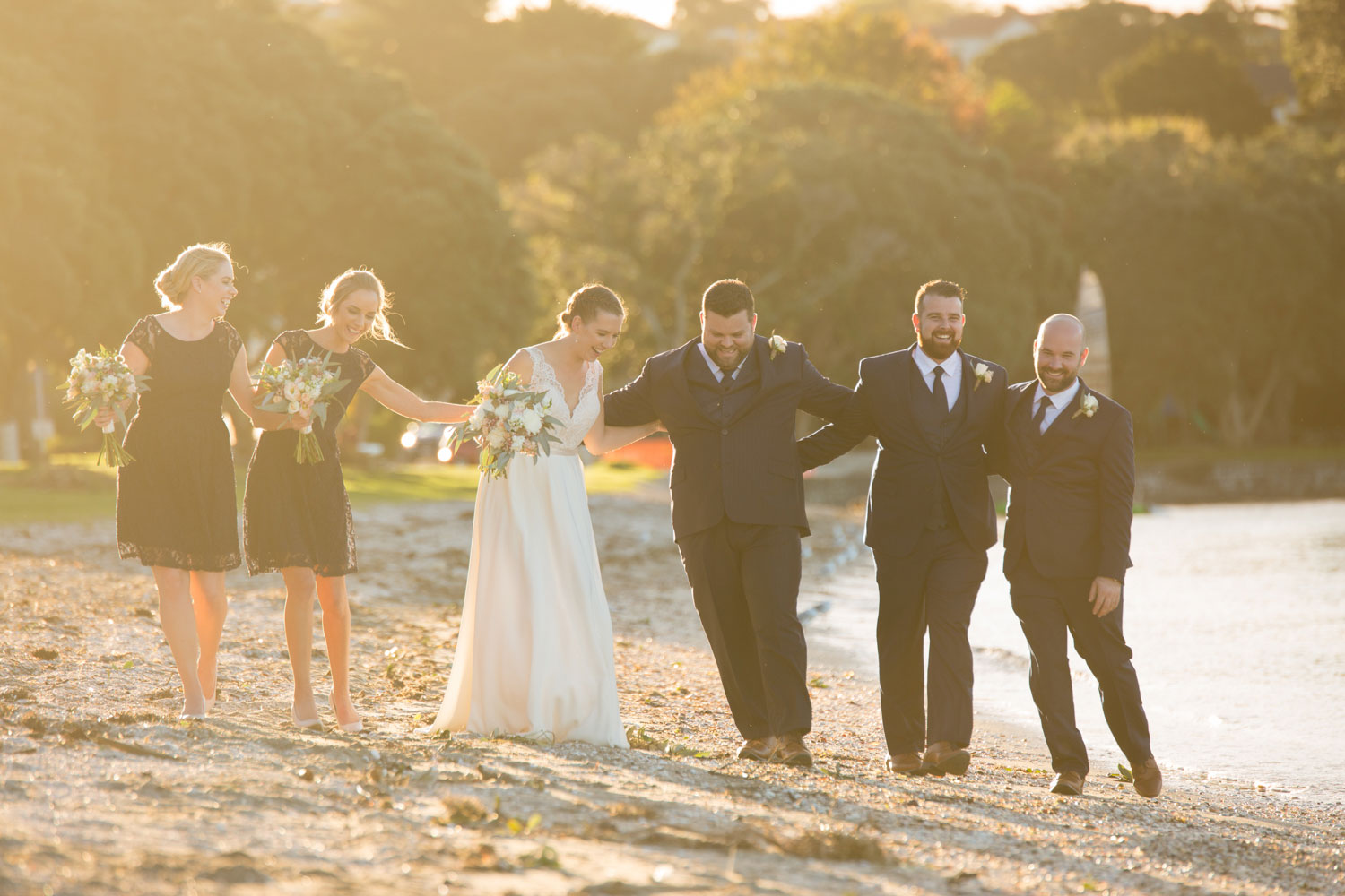wedding photographer auckland bridal party strolling on sand