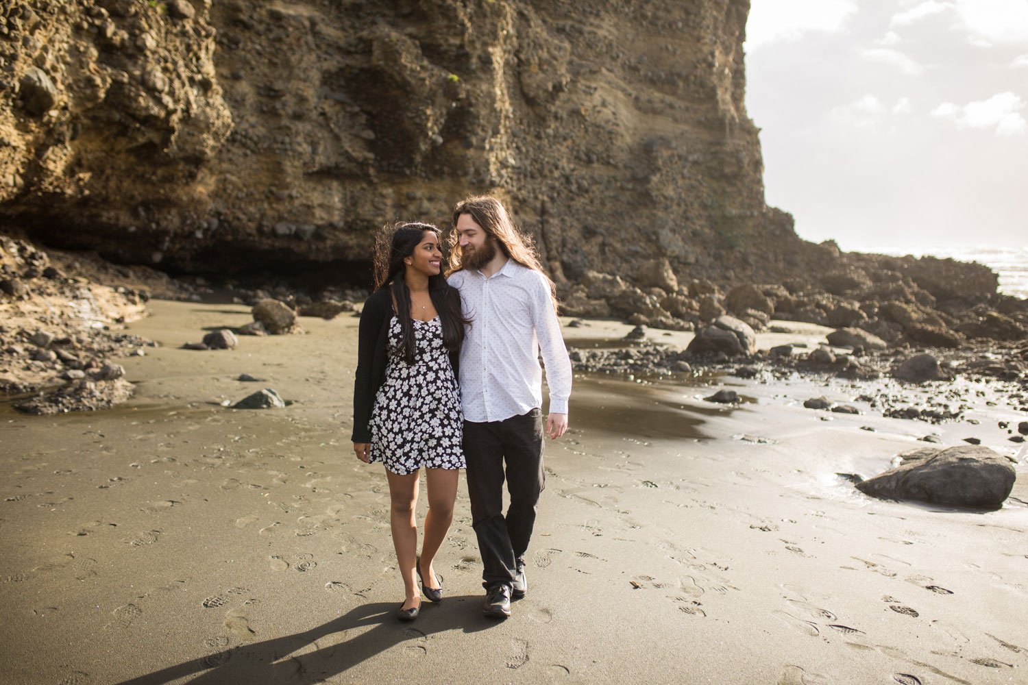 auckland engagement photos couple walking on beach