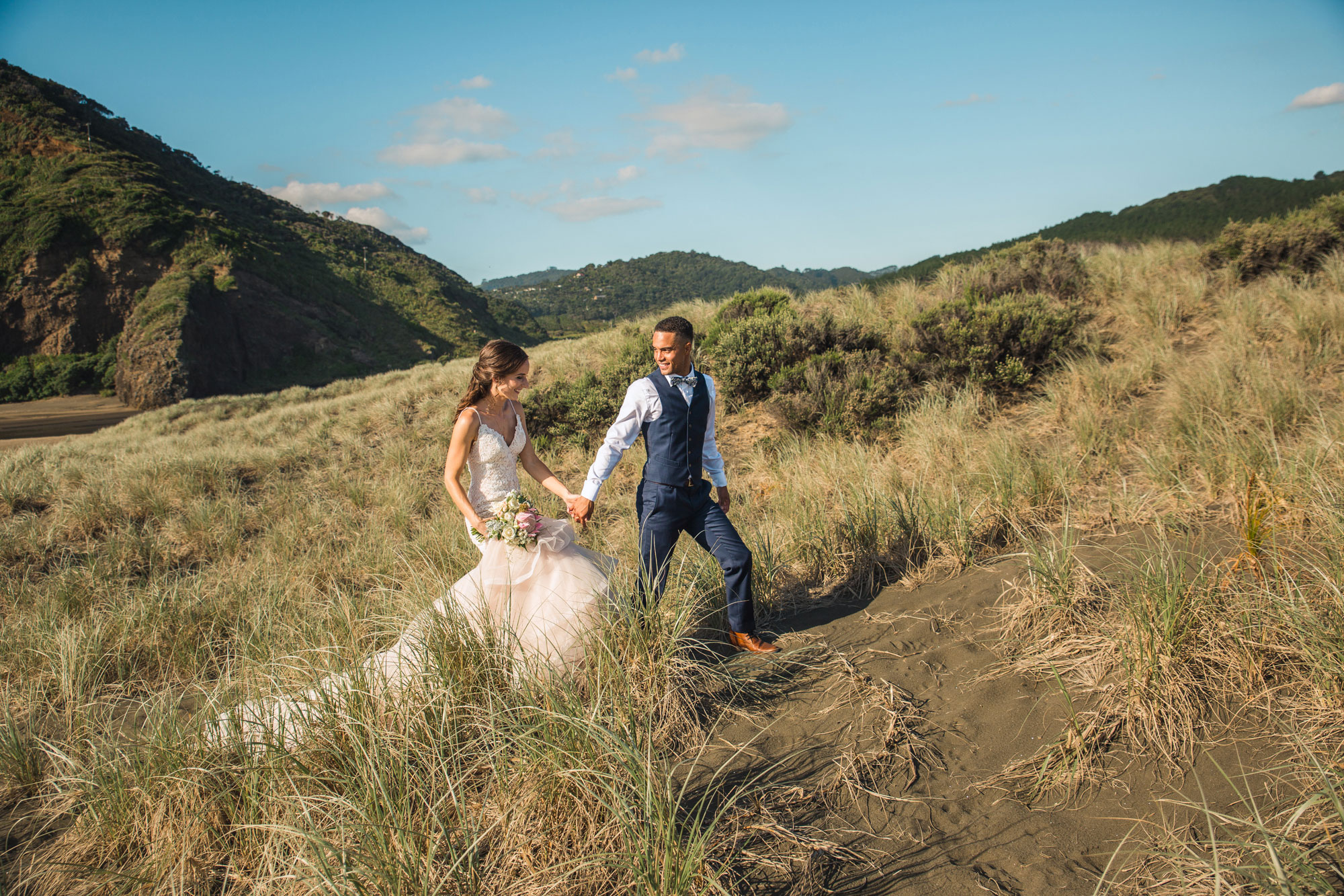 bride and groom walking on dunes