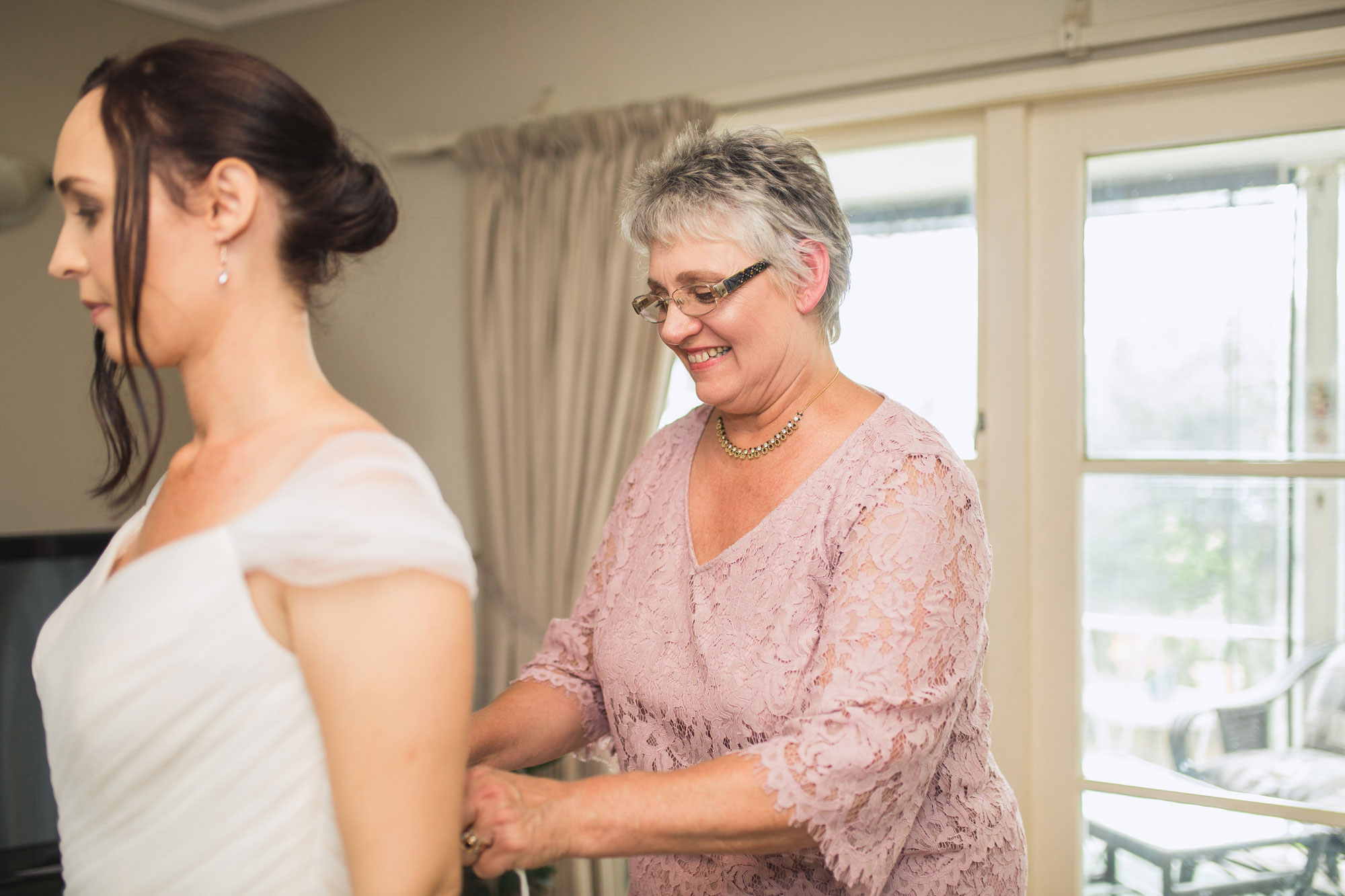 mother tying up bride's dress