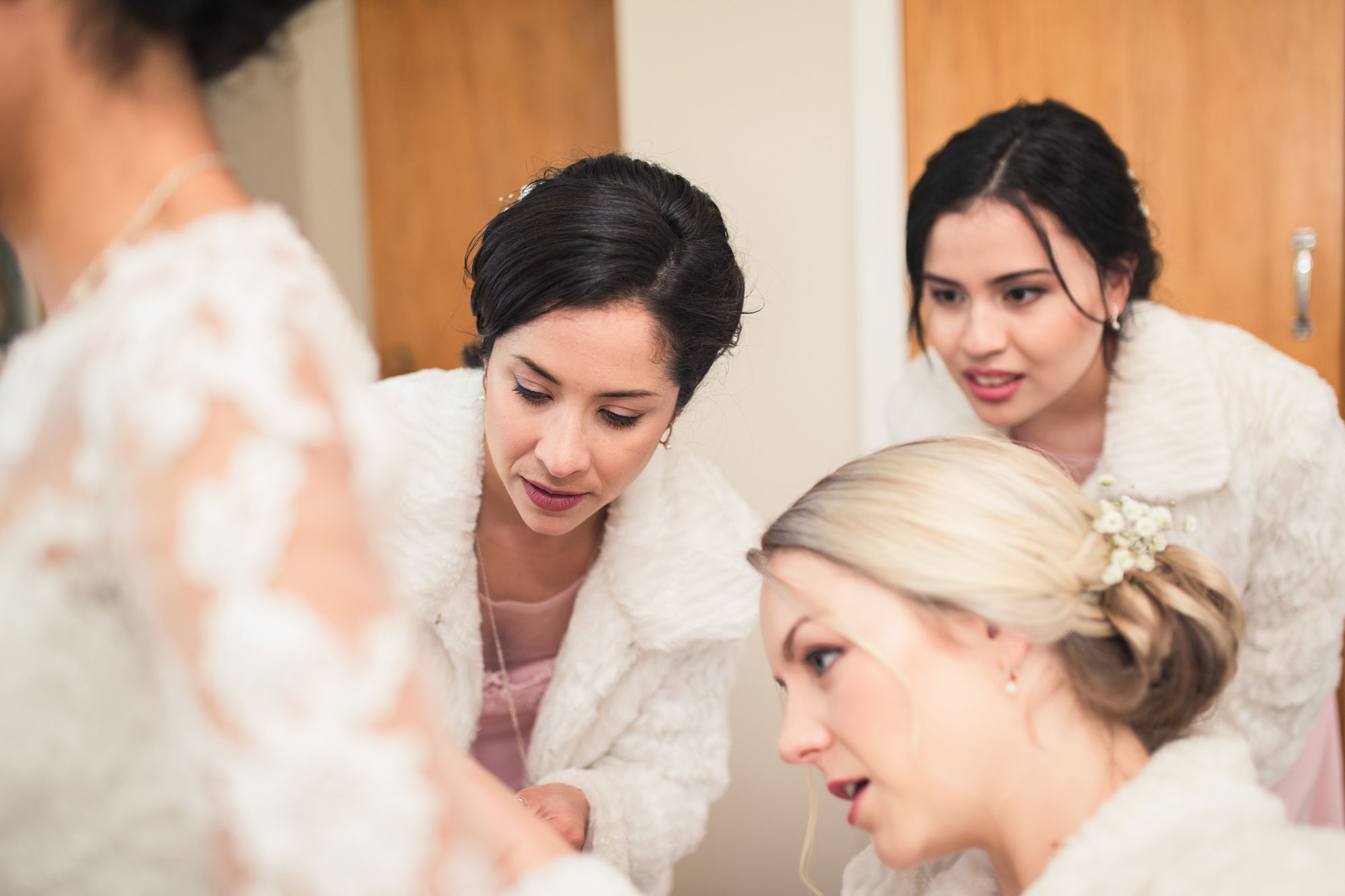 bridesmaids helping bride with her dress