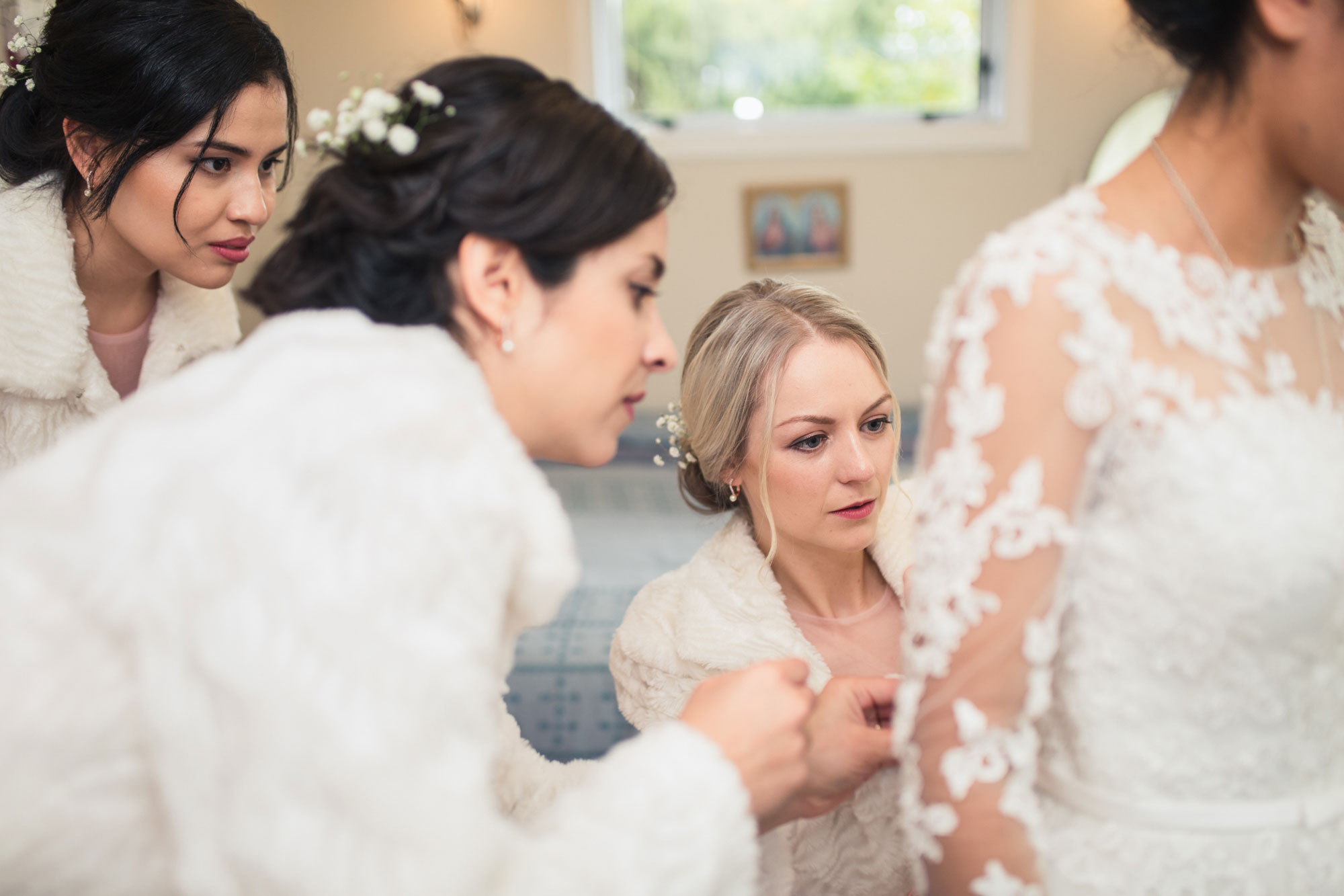 bridesmaid helping bride get dressed