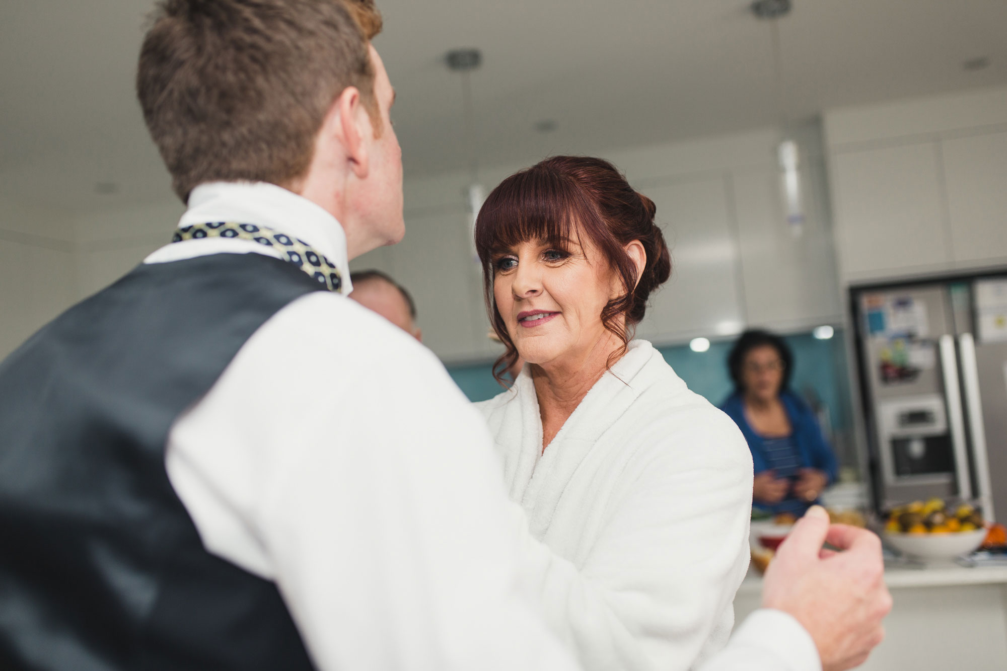 bride putting on tie for son