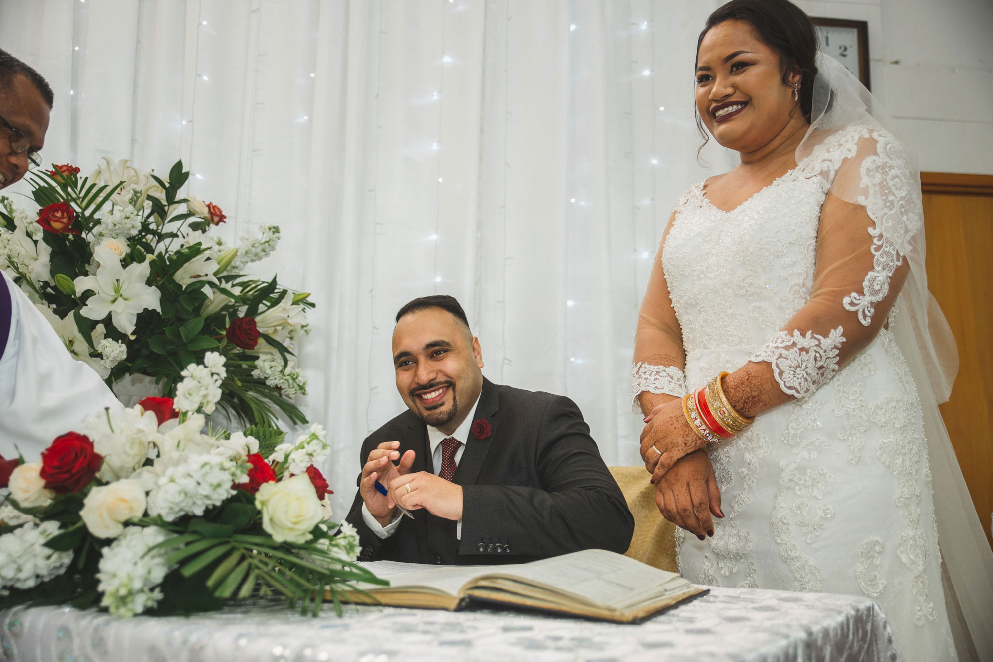 bride and groom laughing while signing