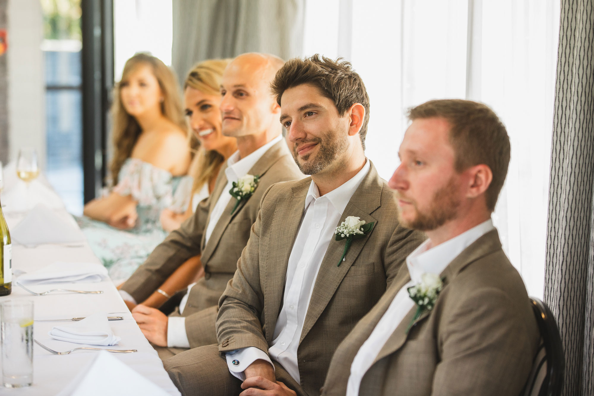 castaways wedding groomsmen listening to speech