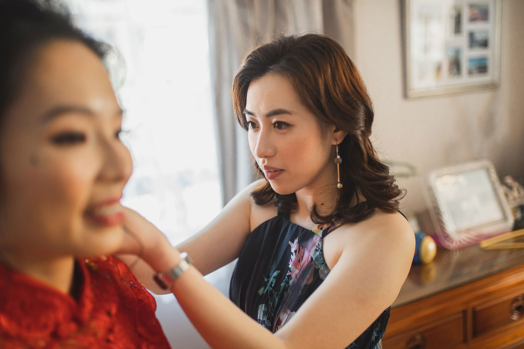 bridesmaid putting on earrings for bride