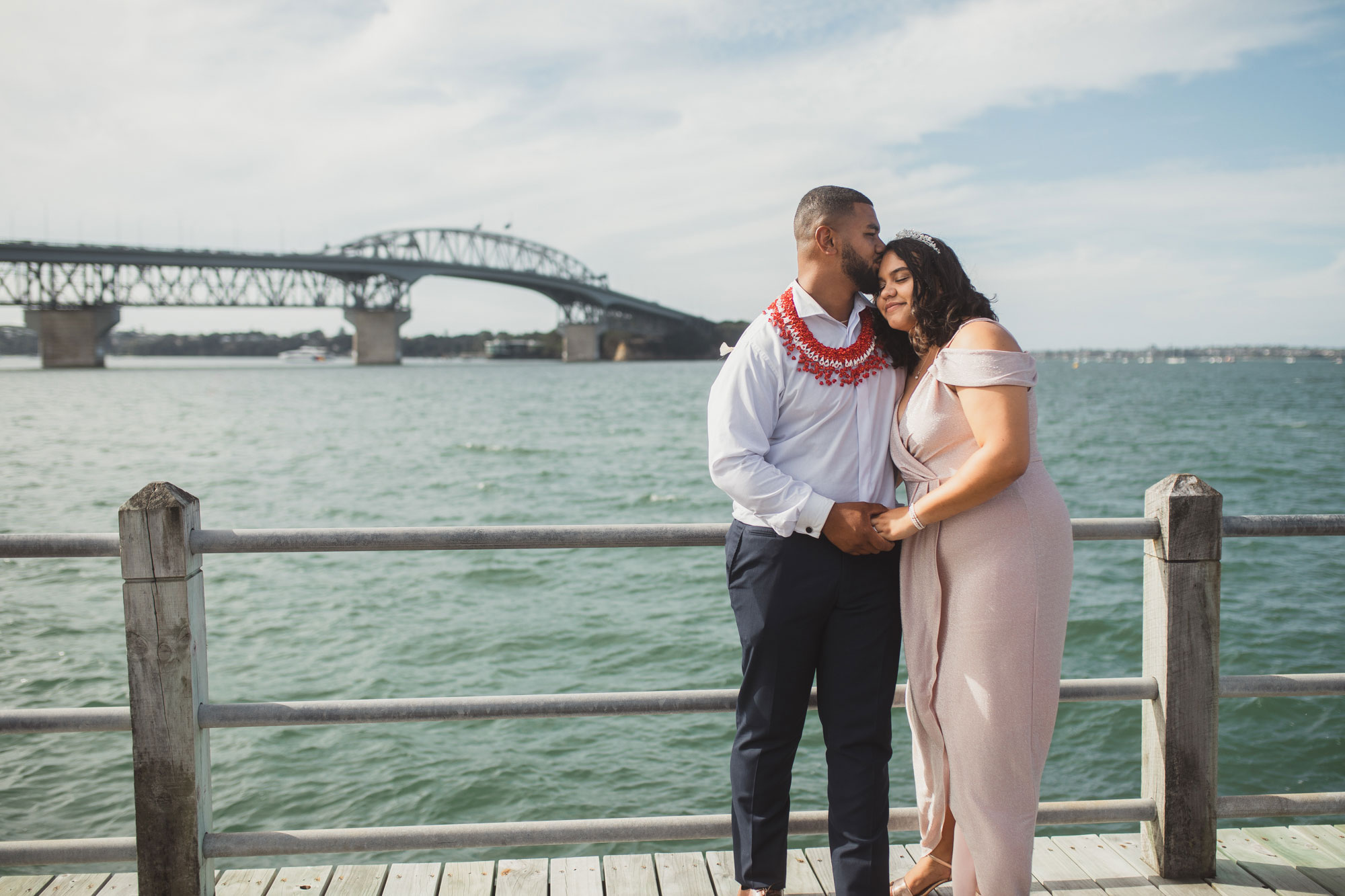 bride and groom kissing by the auckland harbour bridge