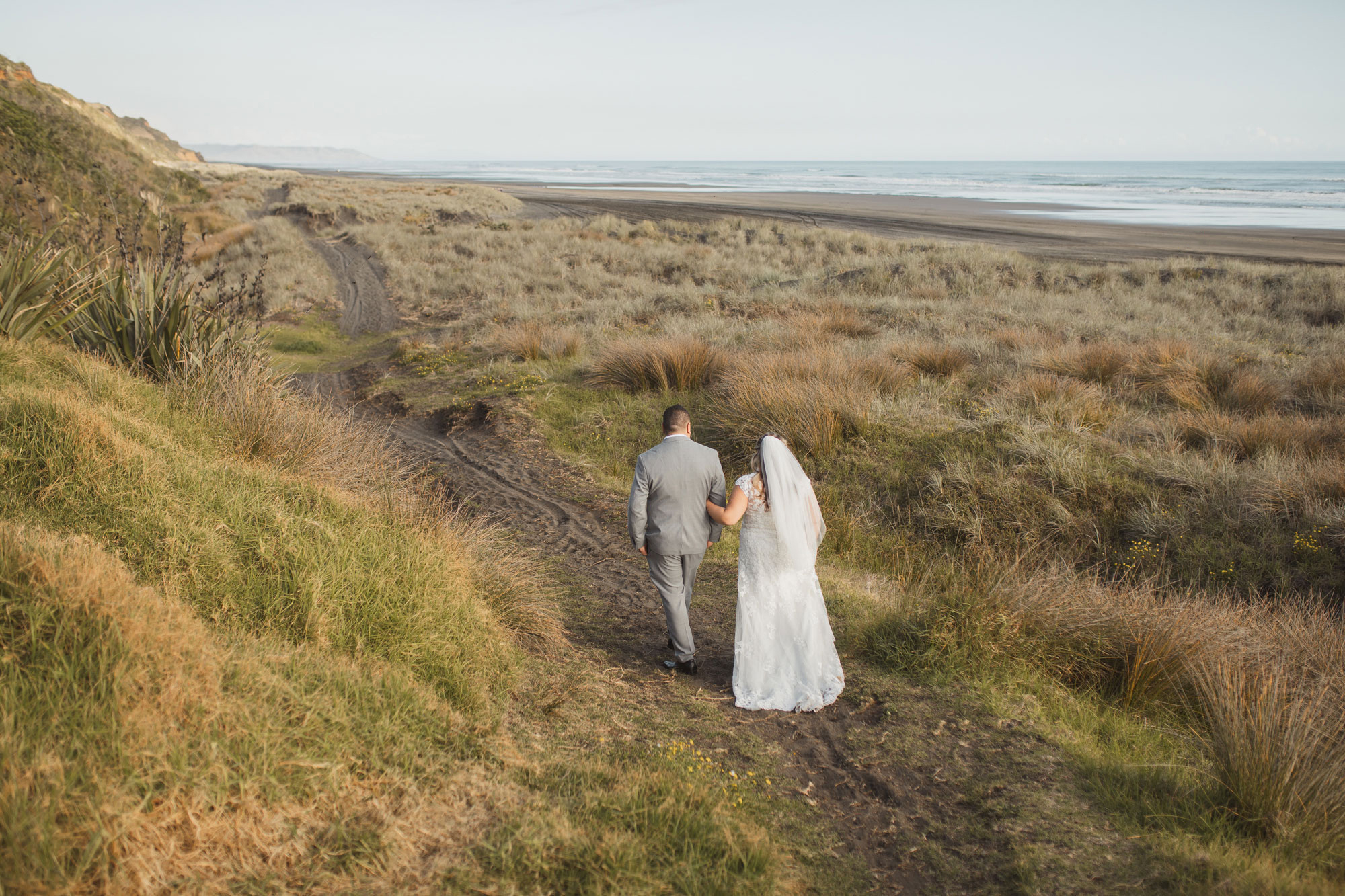 bride and groom walking on auckland beach