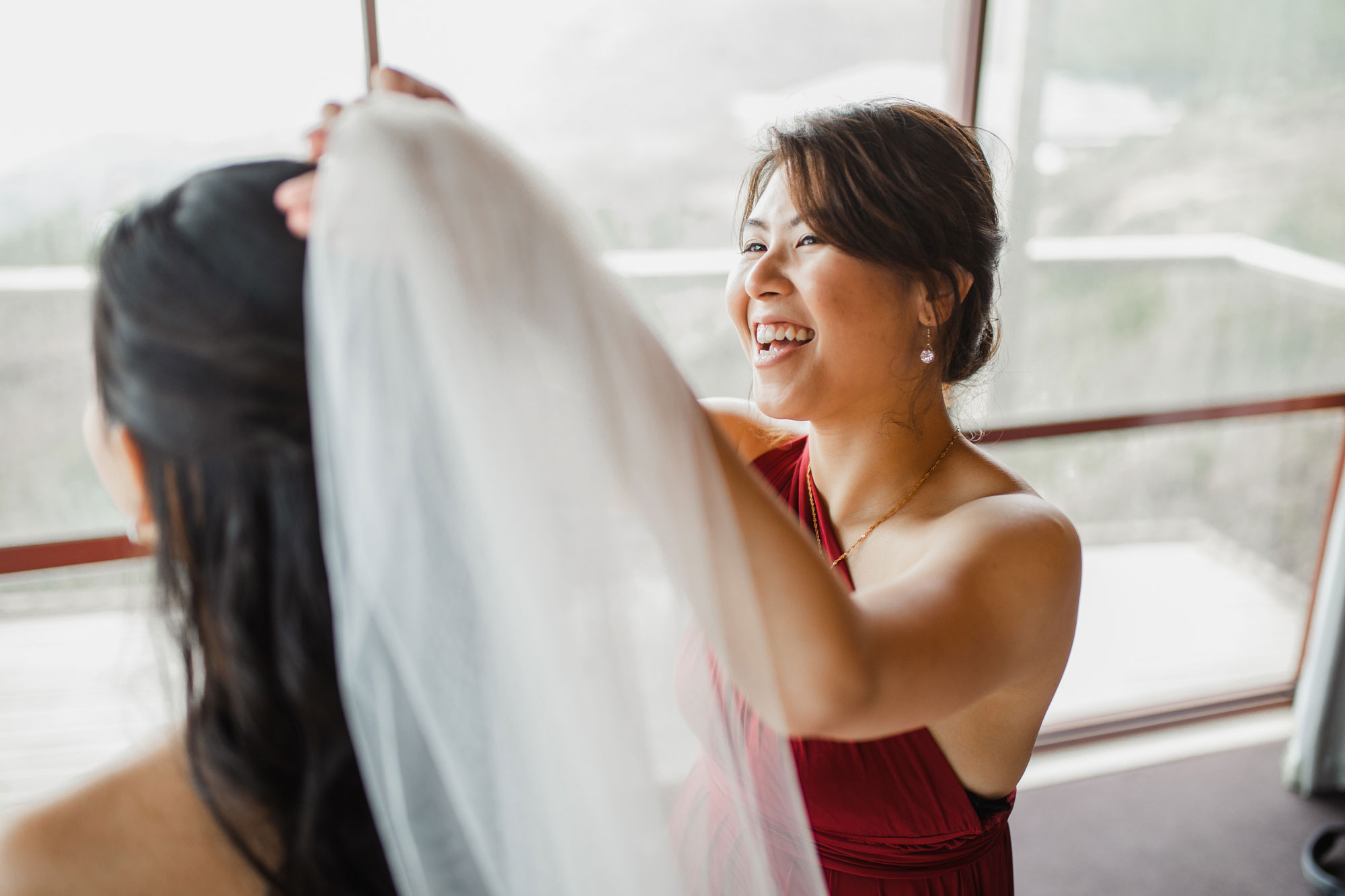 bridesmaid putting on veil for bride