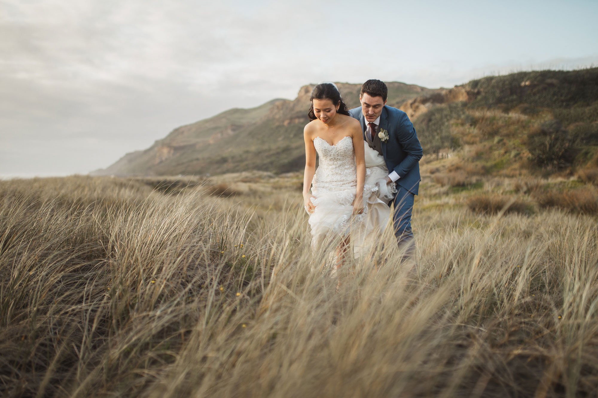 bride and groom walking in grass