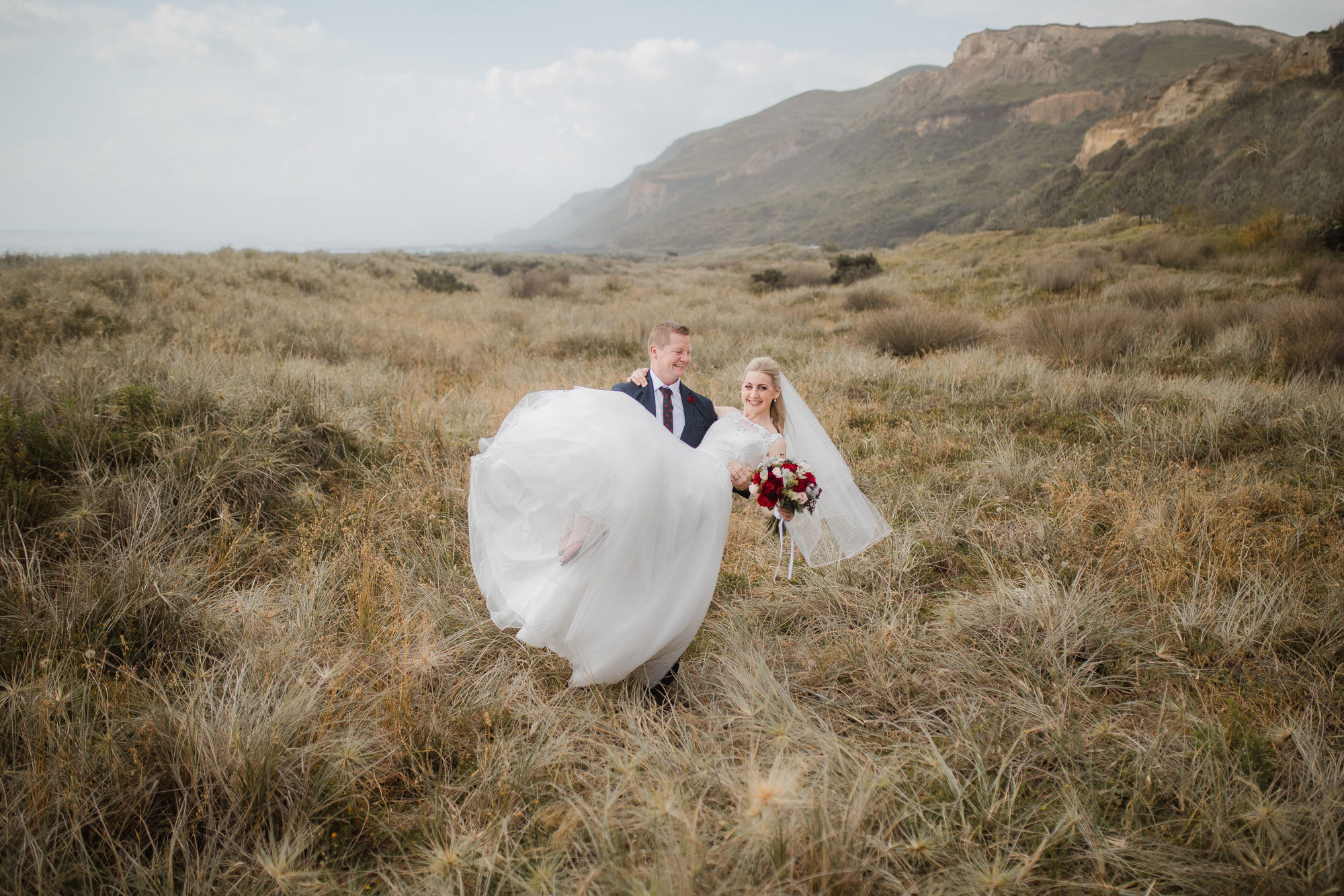 groom carrying bride on the beach