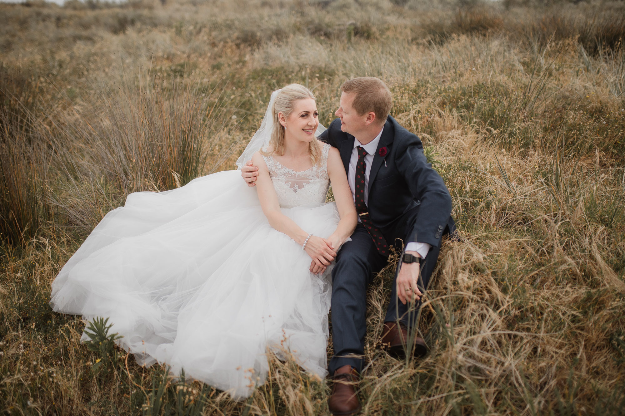 bride and groom sitting on the beach