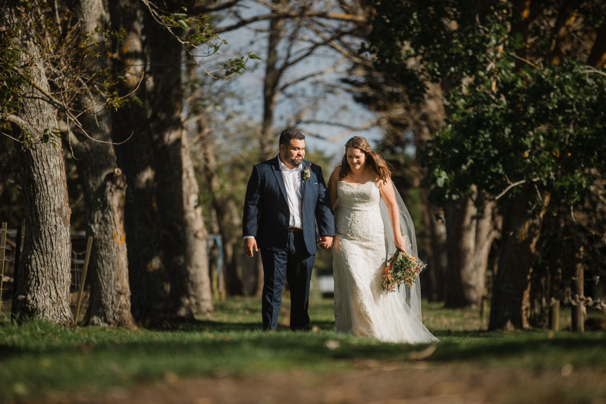 bride and groom walking through forest