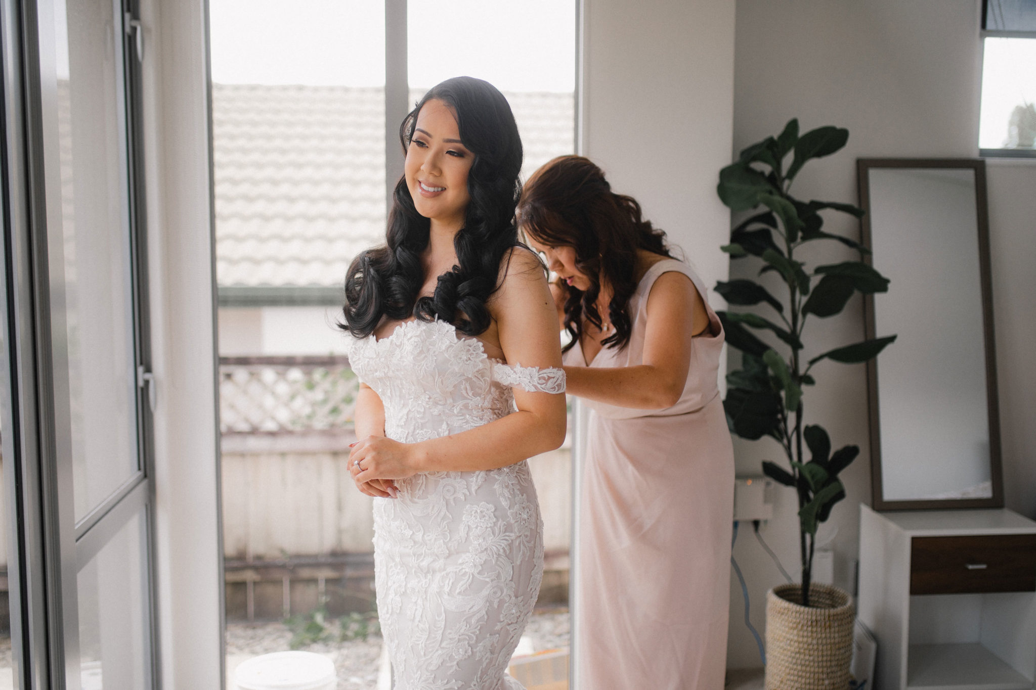 mother helping the bride into her dress