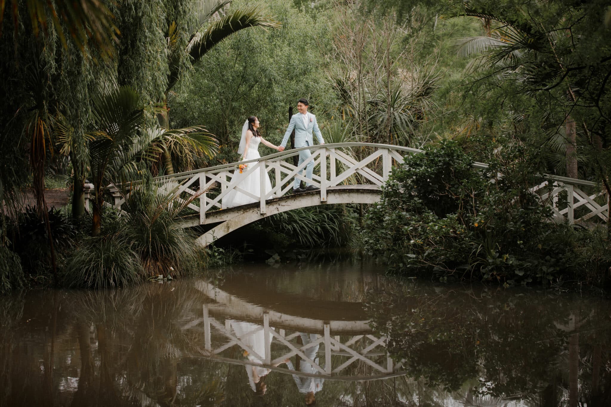 bride and groom walking across bridge