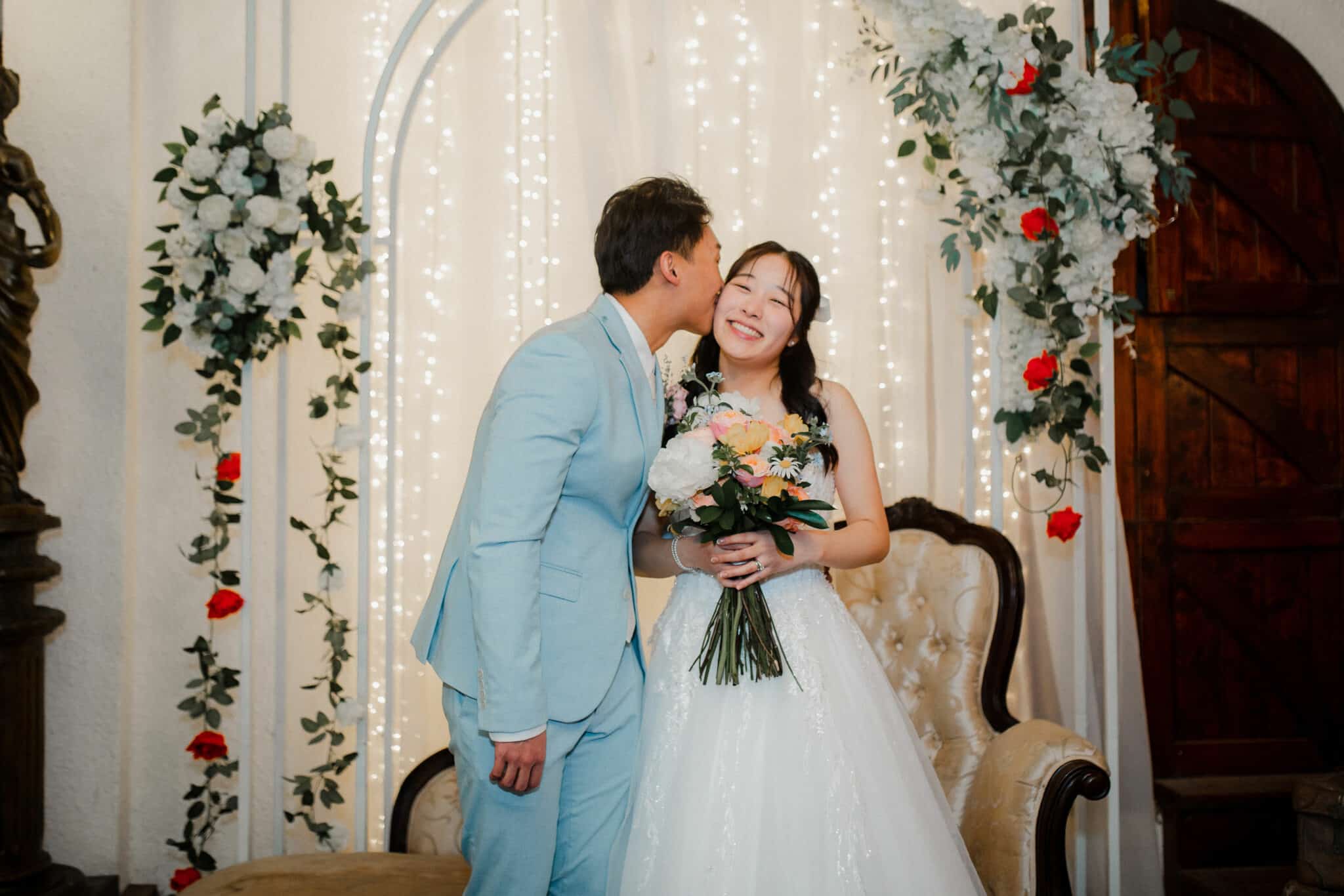 groom kissing the bride with fairy lights