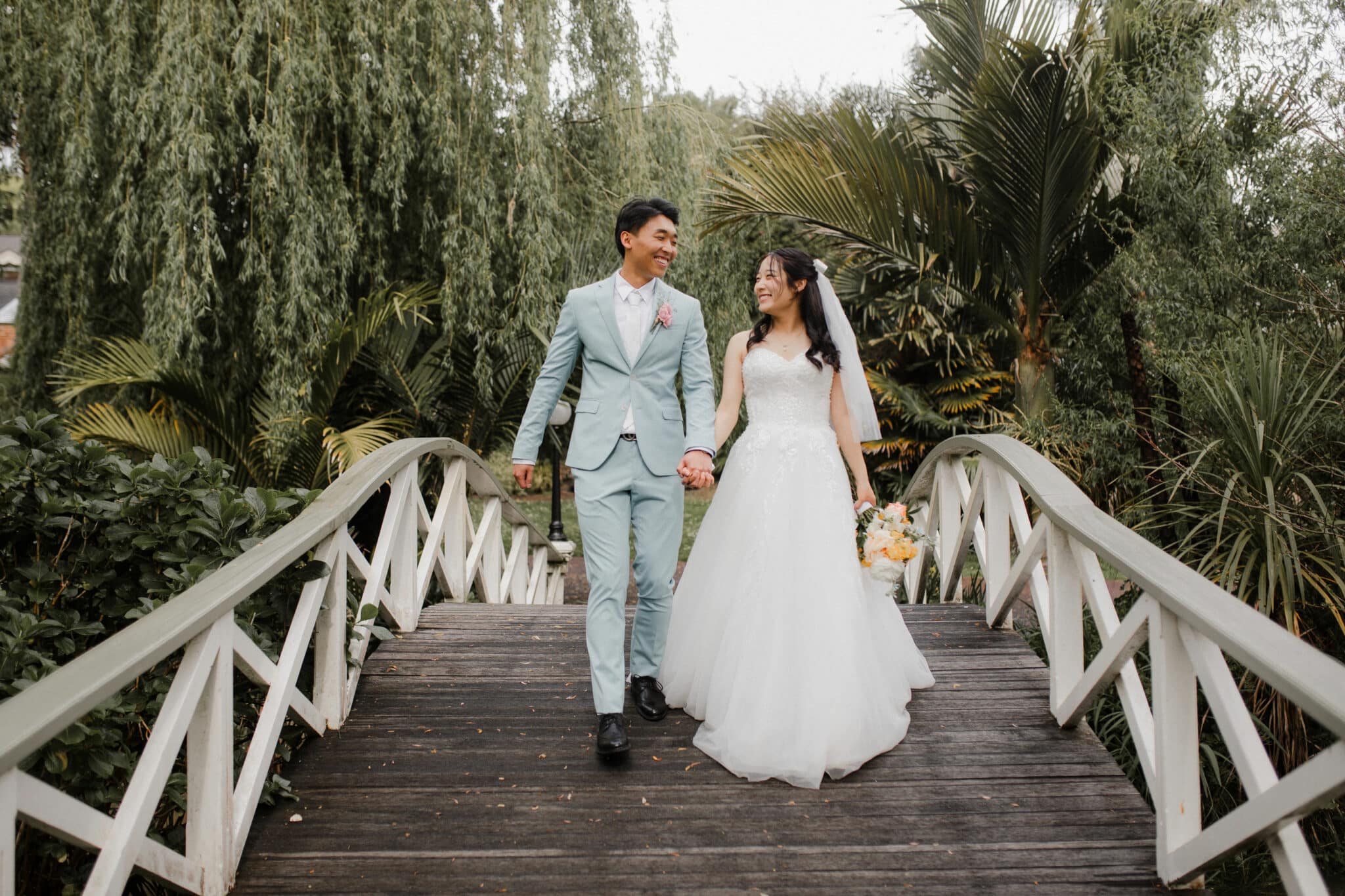 bride and groom walking on bridge